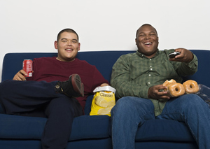 Father and son 16-17 watching TV and eating