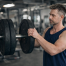 Man adding plates to a barbell hoping that getting stronger will make him bigger