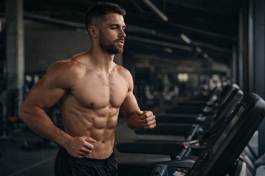shirtless man showing six pack abs doing cardio on treadmill for fat loss
